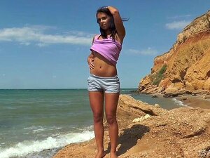 Magdeline setzt sich auf ihre Shorts, um am felsigen Ufer zu