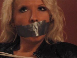 Una bionda sexy in pantaloni di pelle aderenti viene legata e