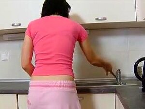 Dasha attend sur le comptoir de sa cuisine seule dans une tenue rose